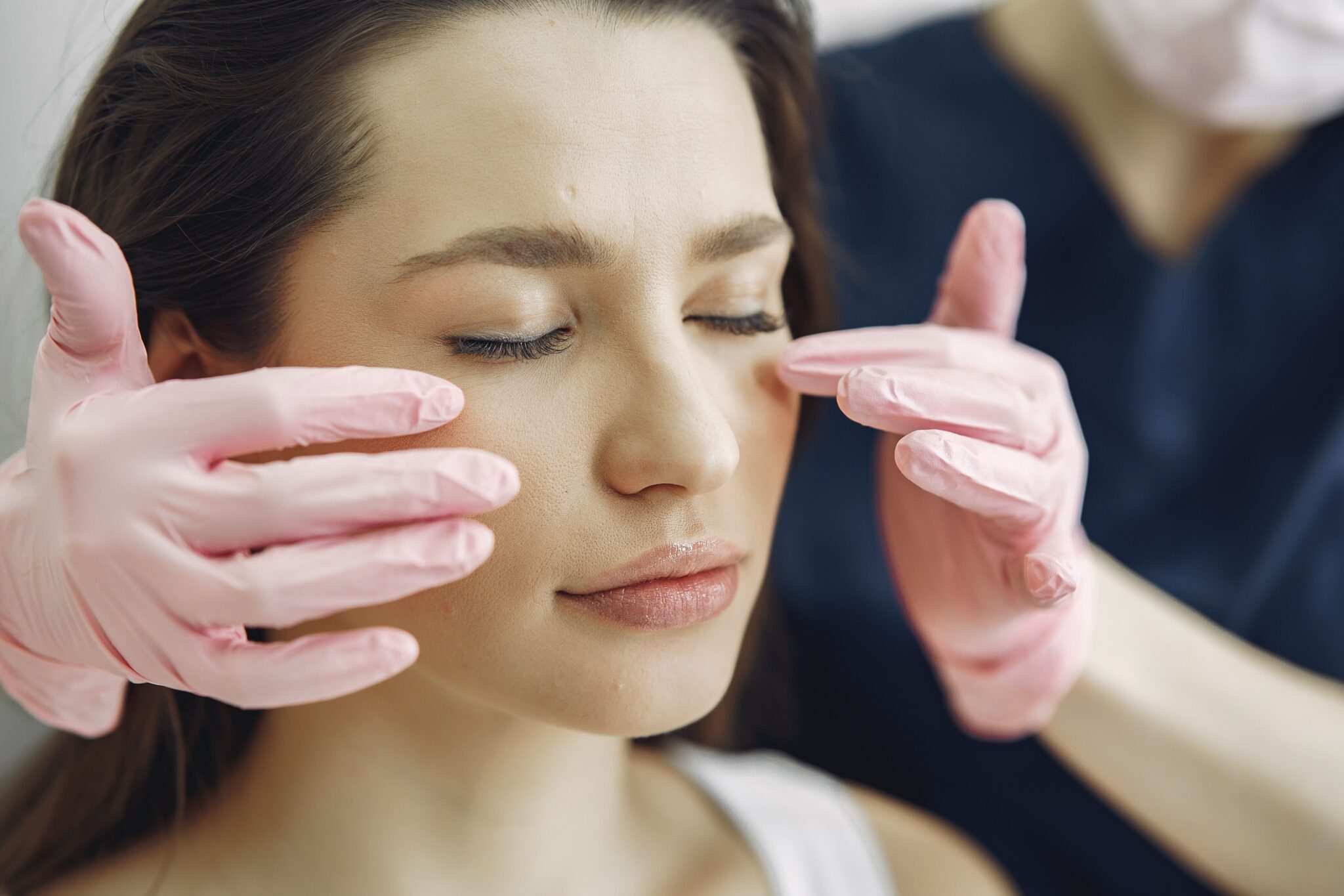 Close-up of a woman with eyes closed receiving facial care in a beauty clinic indoors.
